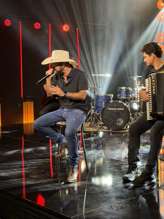 Tonny Ferrari cantando sentado no palco