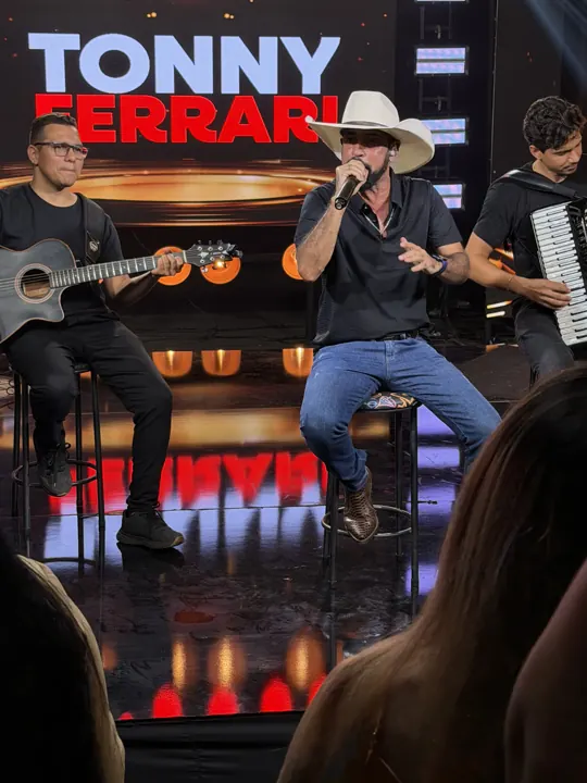 Tonny Ferrari sentado com os músicos no palco
